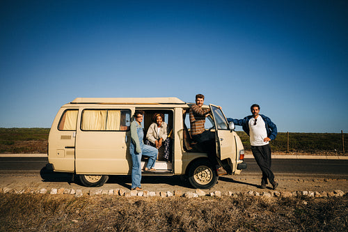 Family and friends on a road trip with a vintage van by the highway today