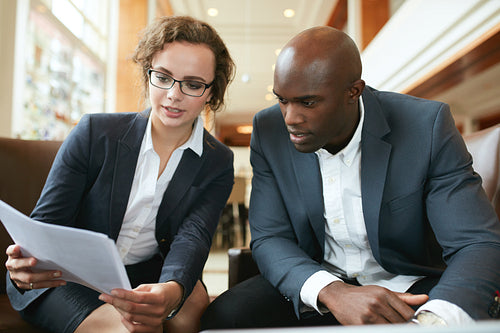 Business executives going through papers in lobby
