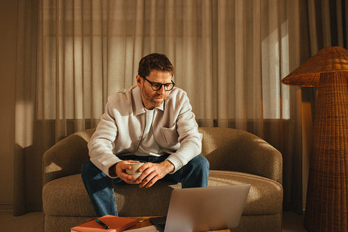 Focused man reviewing work on laptop in office lounge