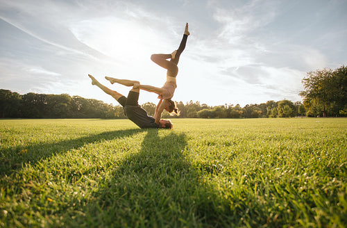 Healthy couple doing acro yoga on grass