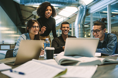 Group of students studying together using laptop