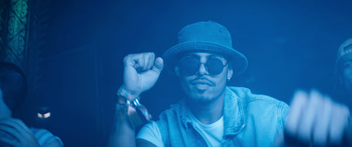 Young man wearing sunglasses dances at a rave