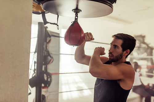 Young man working out with a speed bag in a gym