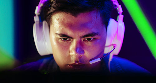 Through the eyes of a gamer: Young man looking at a computer screen with focus while playing a video game