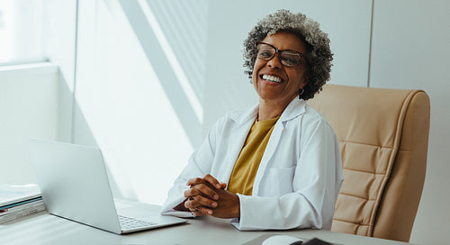 Female dentist smiling at office desk with laptop