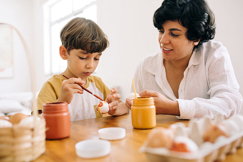 Boy with his mom preparing eggs for Easter