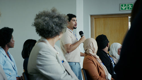 Speaker addressing a diverse audience with a microphone at a business conference