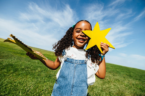 Girl enjoying creative play with stars in grassy field