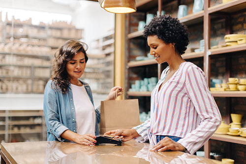 Cheerful shop owner scanning a credit card in her ceramic store