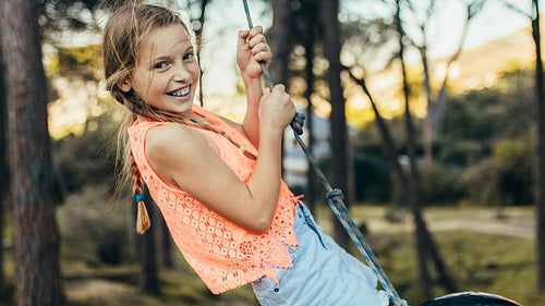 Smiling girl playing on a tire swing in a park