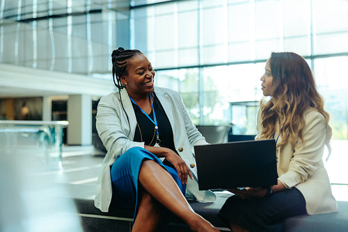 Professional female colleagues discussing in a bright lobby area