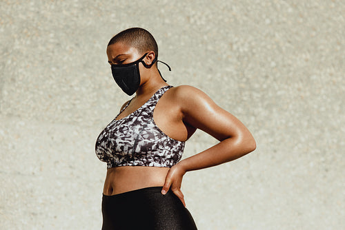 Healthy woman with face mask resting after training session