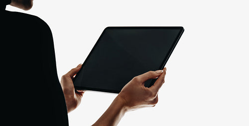 Person holding a modern tablet device against a light background