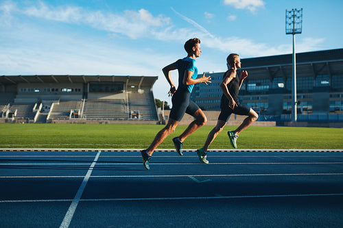 Young men running on race track