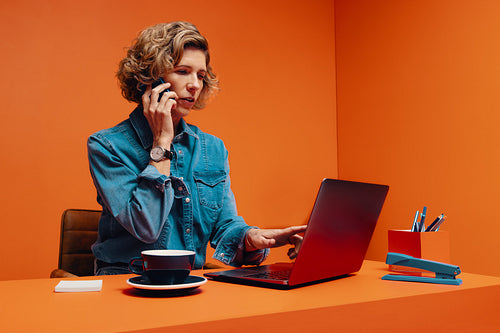 Entrepreneur woman strategizing business plans over the phone while working on laptop
