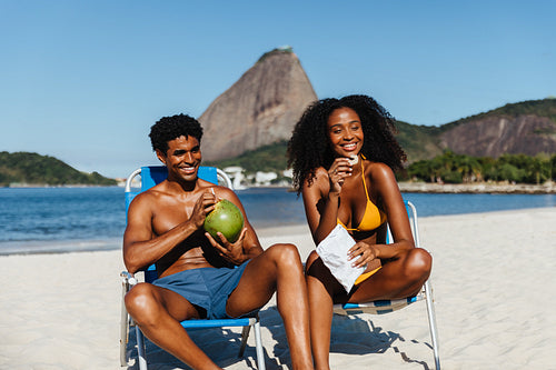 Happy couple enjoying a sunny day at Praia do Flamengo beach with Sugarloaf Mountain in the background