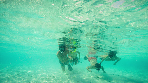 Fun family snorkeling together in crystal clear tropical ocean waters on a summer holiday