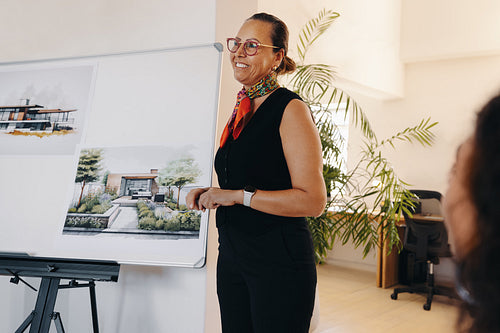 Mature woman leading project meeting with architectural design presentation
