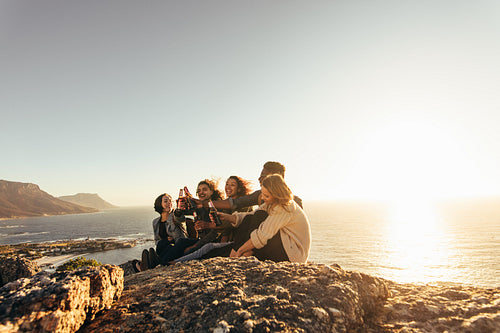 Group of friends toasting beers during sunset