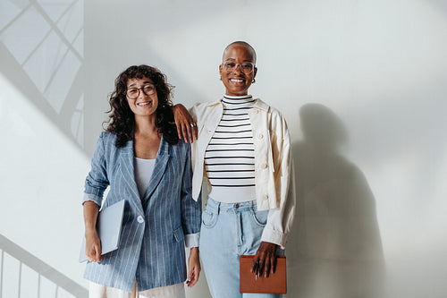 Diverse group of businesswomen smiling and standing in a modern office