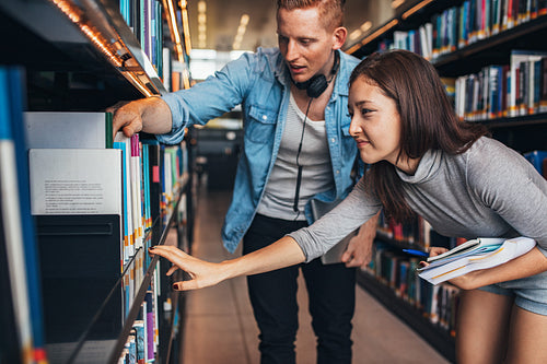 Young students finding reference books in university library