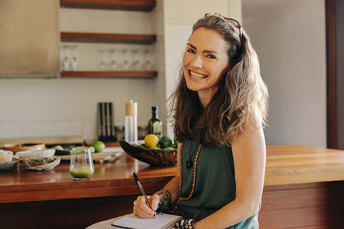 Vegan woman writing down her meal plans and recipes in her diary