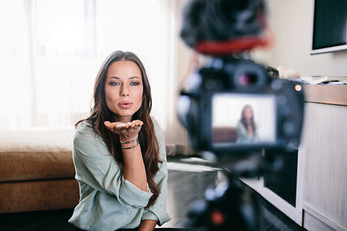 Young woman recording her video on camera mounted on tripod.