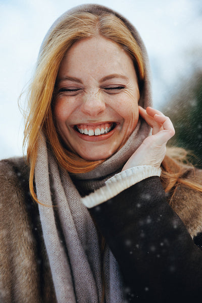 Laughing woman enjoys falling snow in a winter portrait