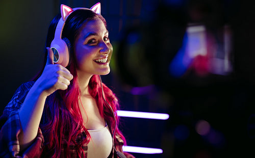 Happy female gamer doing a thumbs up for the camera as she lice records a gaming session