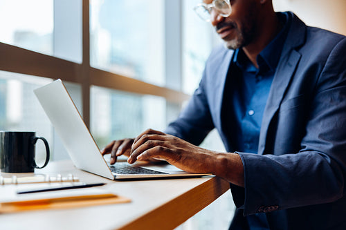Man in glasses working on a laptop in an office environment