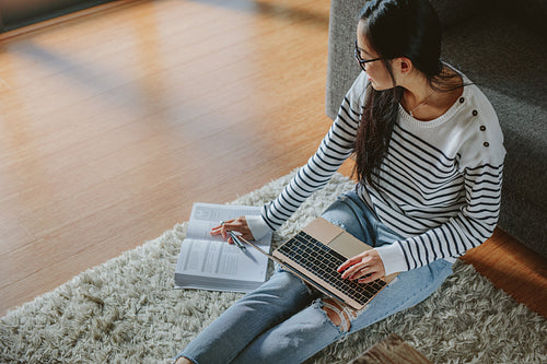 Woman studying with book and laptop at home