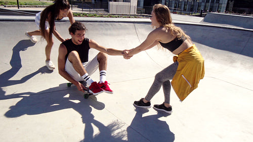 Two young women having fun with their friend in a skate park
