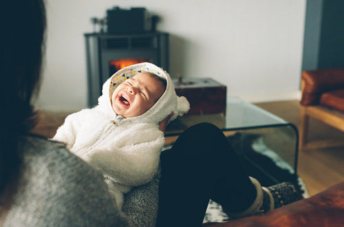 Newborn baby boy crying on his mother's arms