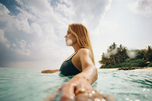 Young woman swimming near tropical beach under a cloudy sky
