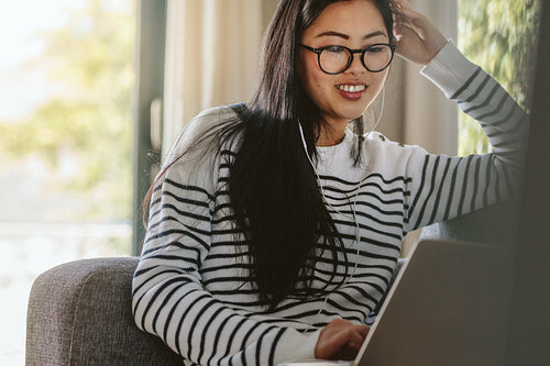 Woman using laptop computer sitting on the sofa