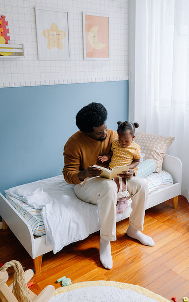 Father reads with daughter in cozy bedroom