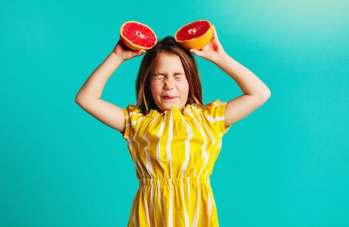 Girl holding grapefruit with dislike expressions