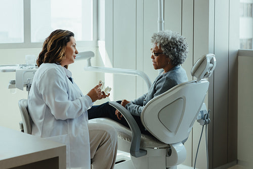 Explaining dental treatment with a tooth model to patient in clinic