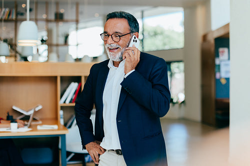 Senior businessman talking on phone inside a bright and spacious office