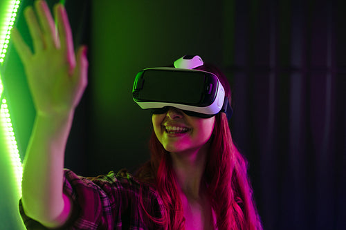 Happy young woman interacting with a VR game using a virtual reality headset