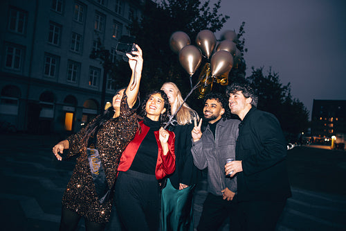 Group of friends smiling and taking a selfie during an evening celebration