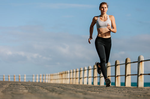 Sportswoman running on a road by the sea