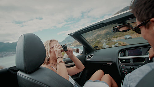 Couple taking photos on a long drive in a open car