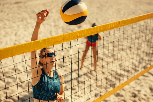 Female athlete engaging in an intense volleyball game on a sunny beach