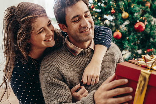 Young couple having fun celebrating Christmas with gifts.