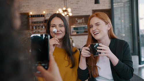 Friends at the cafe taking photographs with a cell phone