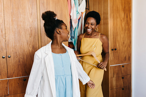 Happy mother and daughter having fun getting dressed in stylish casual clothing