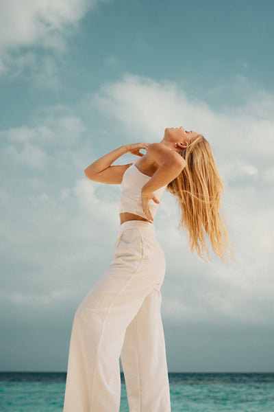 Woman in white embracing freedom by the ocean on a sunny day