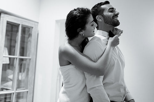 Romantic young woman fixing her husband's tie in a hotel