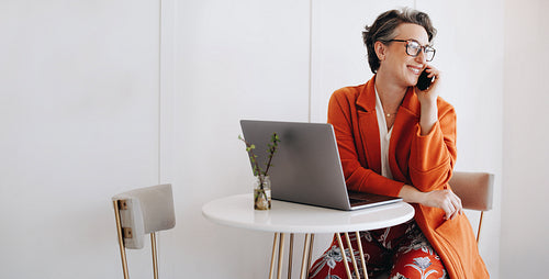 Successful businesswoman speaking to a client on the phone while working in a cafe